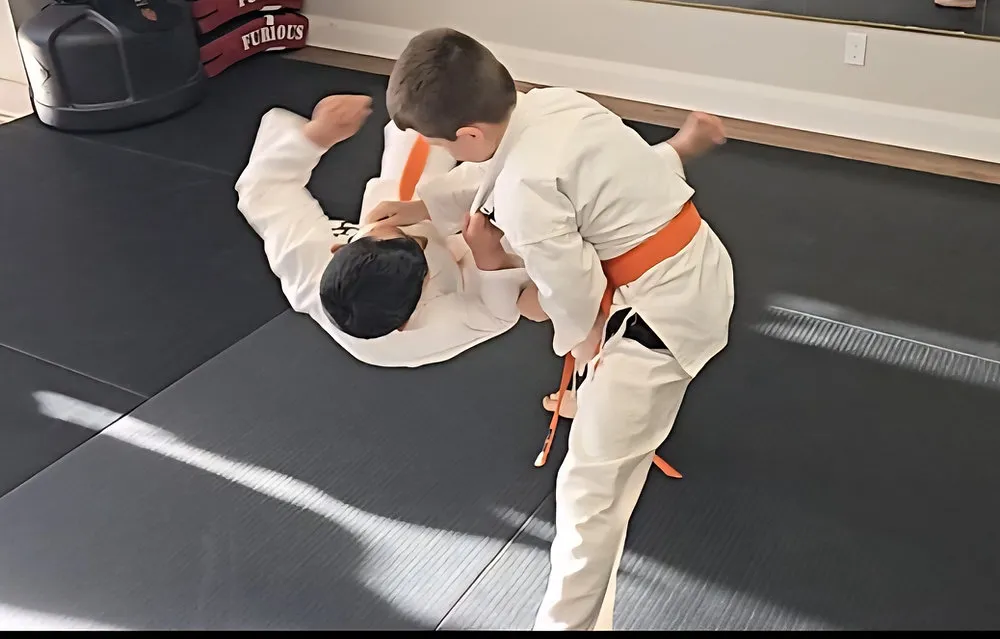 Child practicing self-defense with an instructor in a supportive martial arts class