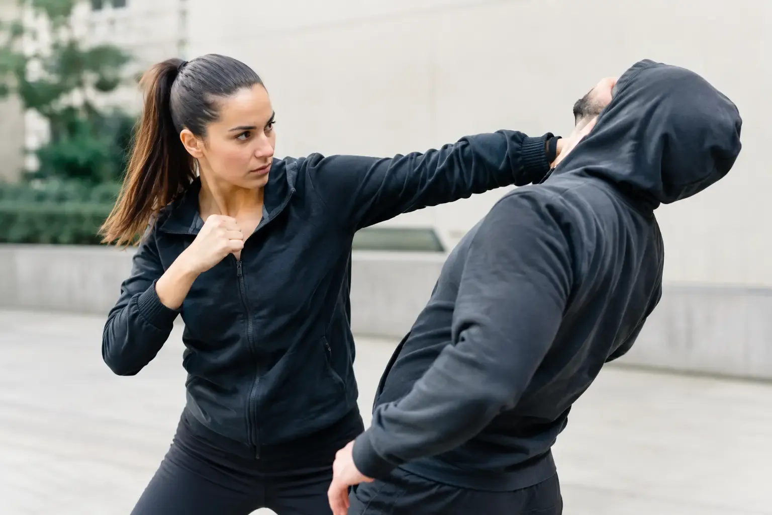 Adult woman practicing a defensive strike against an adult man in a self-defense drill